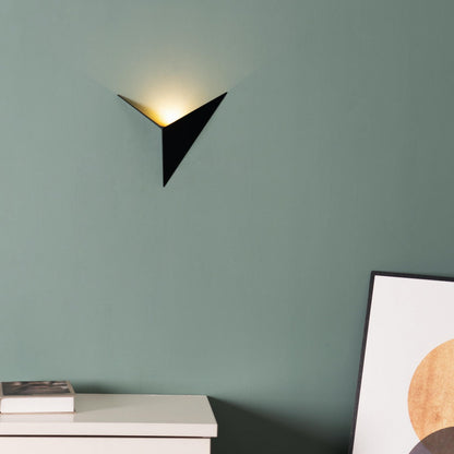 Modern black wall sconce on a green wall with a piece of abstract art in the corner.