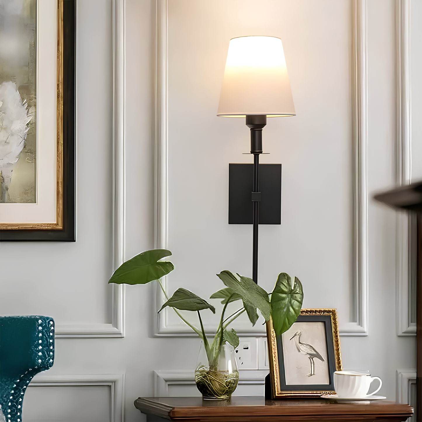 Decorative wall sconce with a plant and framed picture on a wooden surface.