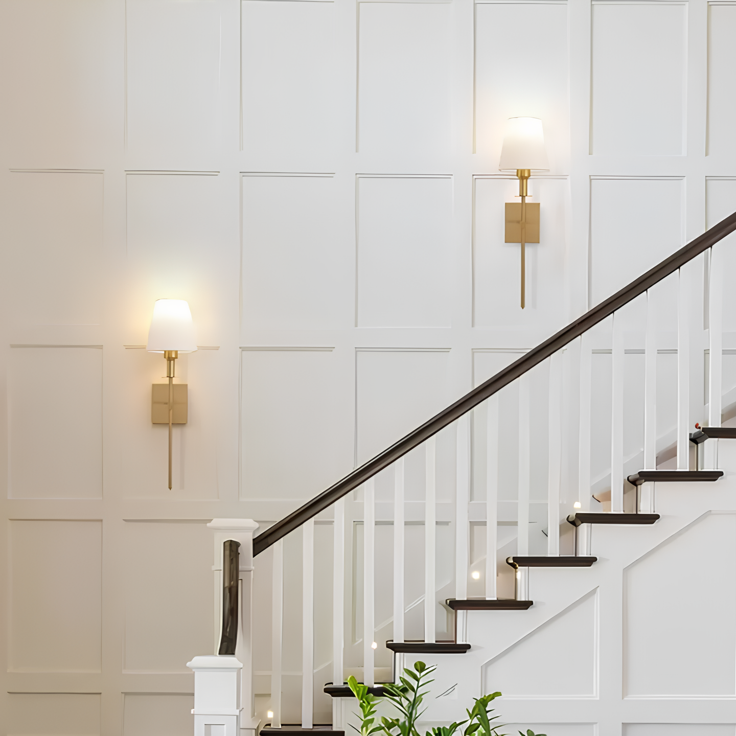 Staircase with white walls and gold wall sconces