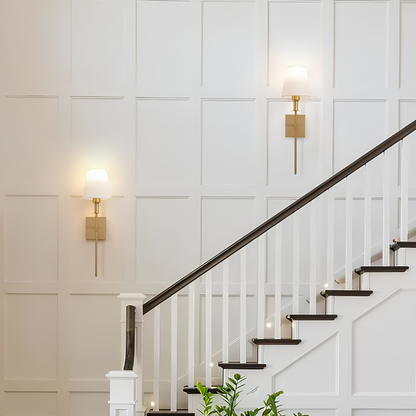 Staircase with white walls and gold wall sconces