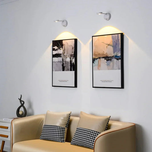 Beige sofa with decorative pillows in a room with abstract wall art and lighting fixtures.