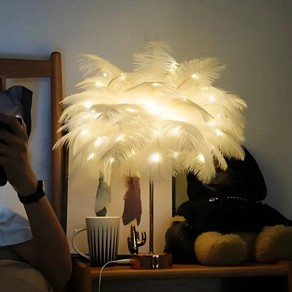 Decorative feather lamp with string lights on a table next to a mug and plush toy.