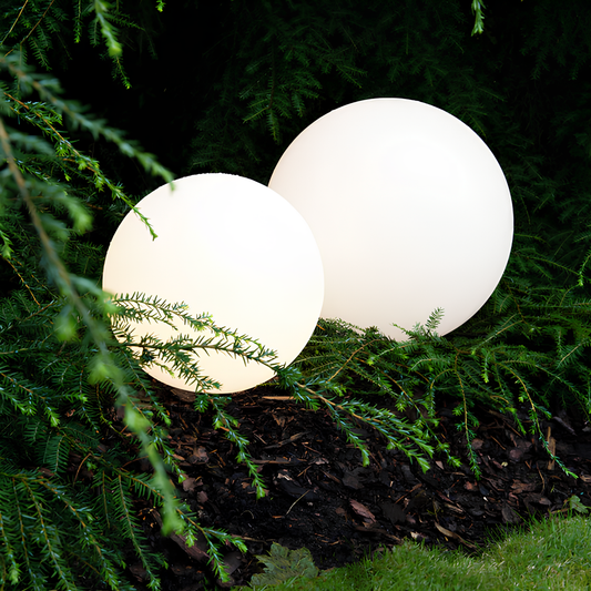 Two spherical white lights nestled among green foliage
