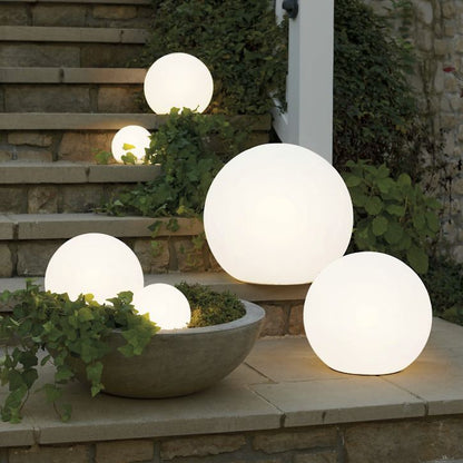 Glowing spherical outdoor lights on a stone ledge with plants.