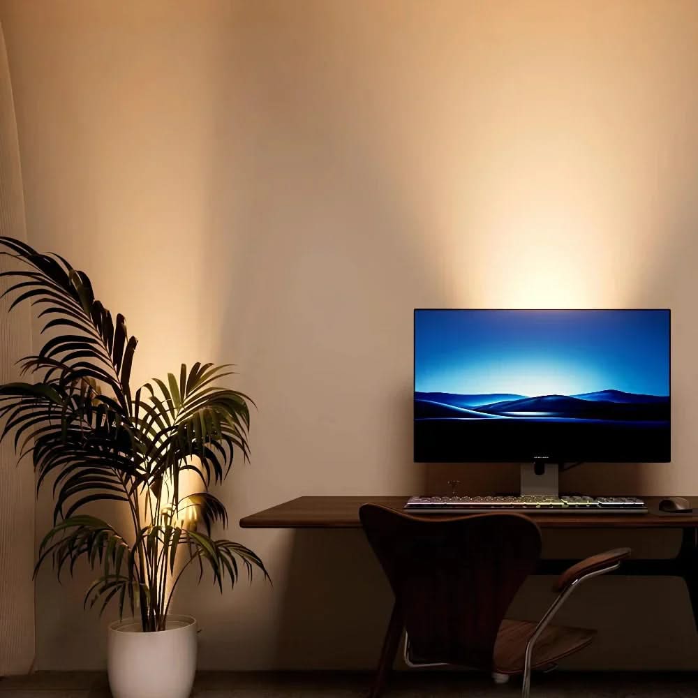 Modern home office setup with a computer monitor, keyboard, and chair against a beige wall.