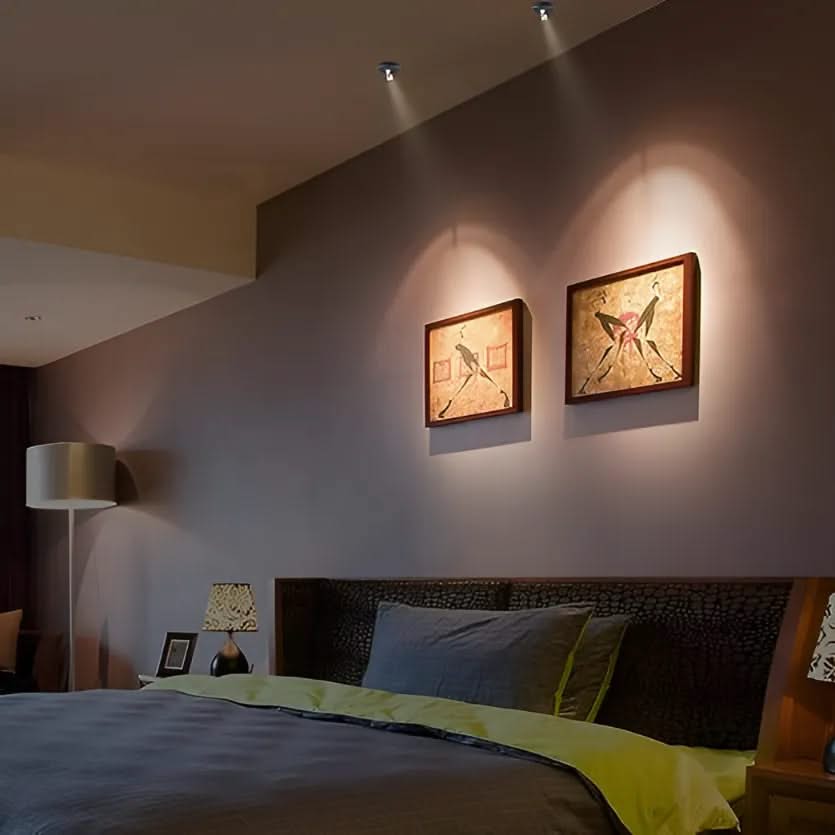 Bedroom with two framed artworks on the wall, a bed with green and blue bedding, and a lamp.