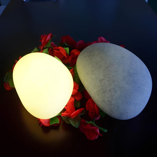 Glowing spherical light bulb on a bed of red flowers against a dark background