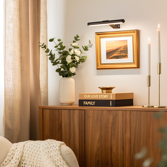 Nestled corner of a room with a wooden cabinet, decorative books, a vase with flowers, and framed artwork.