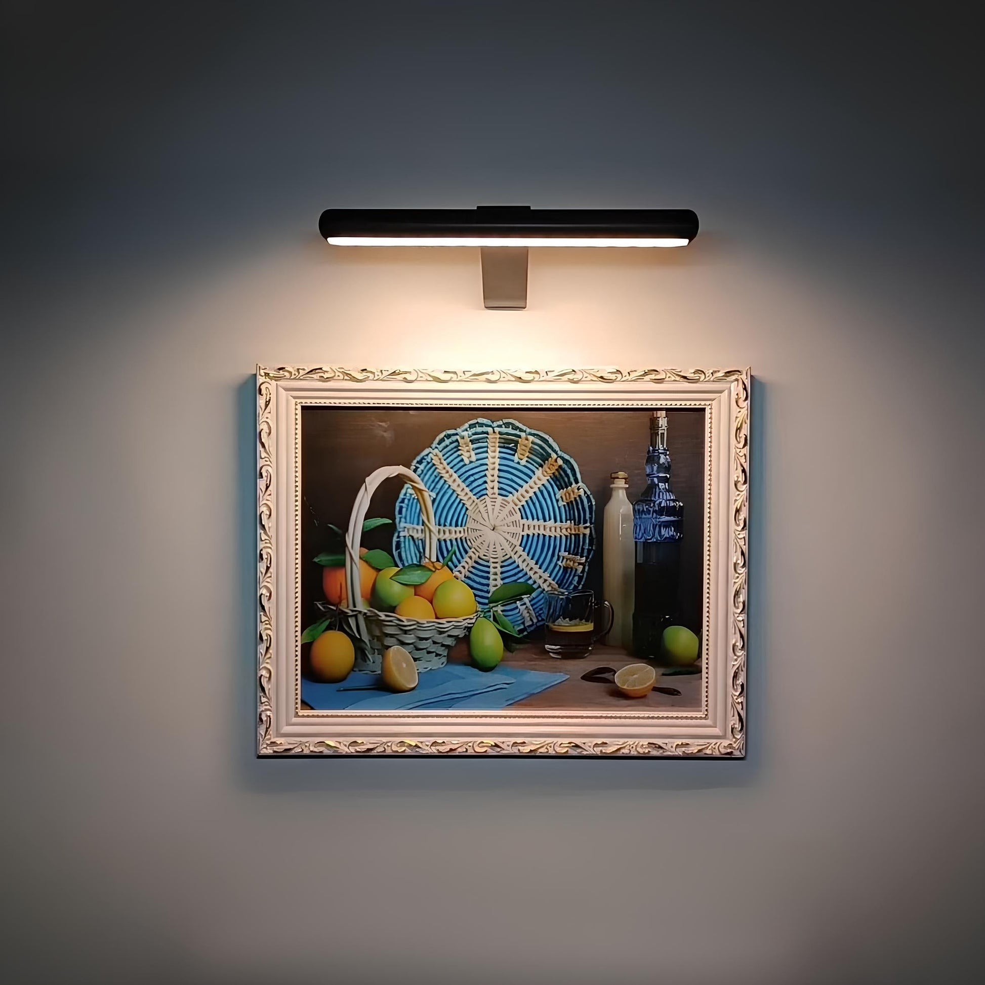 Decorative still life painting with a basket and fruits illuminated by a wall-mounted light fixture.