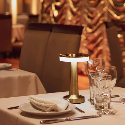 Decorative table setting with a gold lamp and glasses in a restaurant.