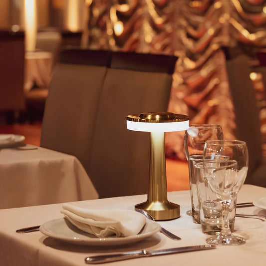 Decorative table setting with a gold lamp and glasses in a restaurant.
