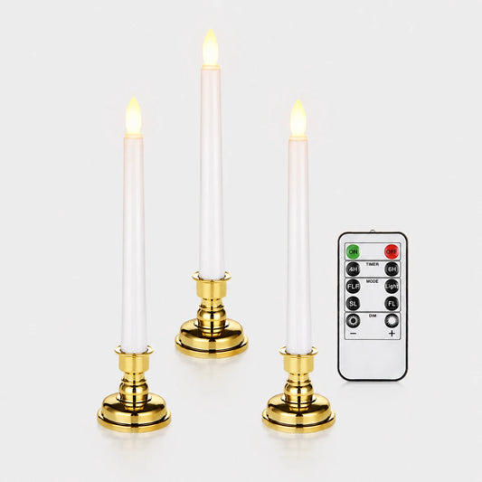 Josh & Tate - LumiCandle Standing LED Light - Three white taper candles with gold bases and glowing flame tips, shown with a black remote control on a light gray background.