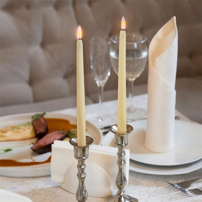 Elegant dinner setting with candles, plates, and cutlery on a table.