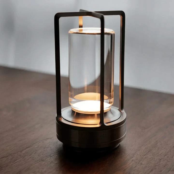 Modern lantern-style lamp with glass cover on a wooden surface
