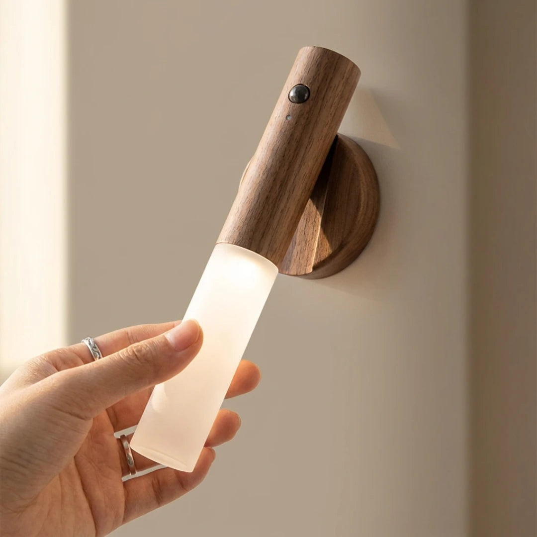 Josh & Tate - LumiDock™ Motion Wall Light - Wooden wall sconce with a hand holding a light bulb against a neutral background