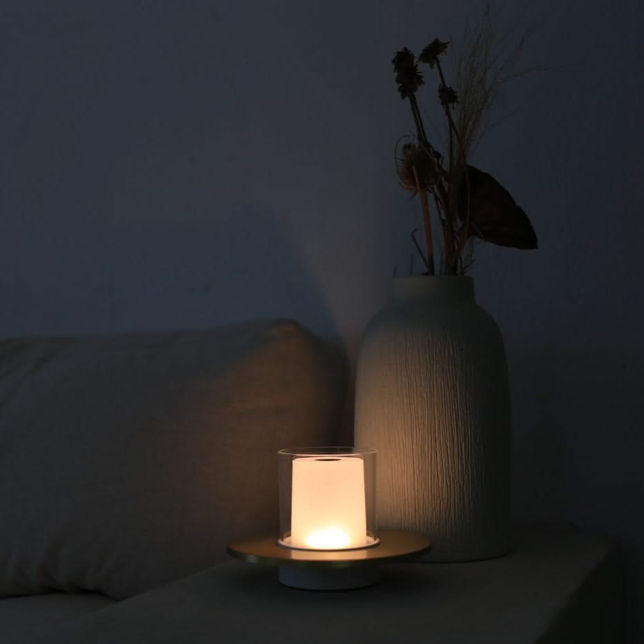 Candle and vase with dried plants on a dark surface
