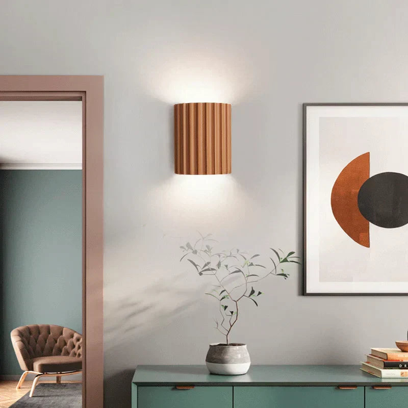 Modern interior design with a wall lamp, plant, and framed abstract art.
