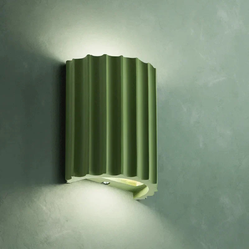 Green wall-mounted light fixture on a gray wall