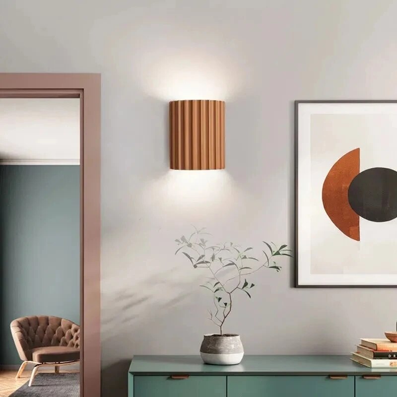 Modern interior design with a wall lamp, plant, and framed abstract art.