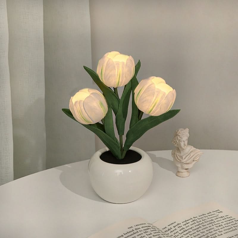 Decorative potted plant with illuminated bulbs on a table next to a classical statue.