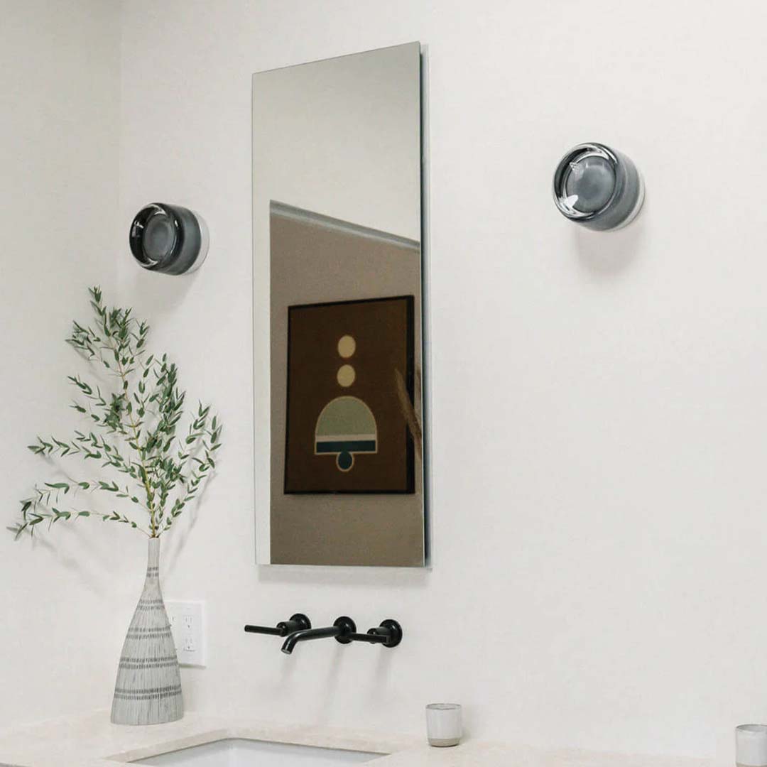 Modern bathroom interior with a large mirror, light fixtures, and decorative elements.