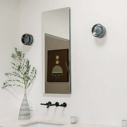 Modern bathroom interior with a large mirror, light fixtures, and decorative elements.