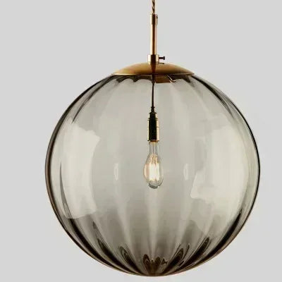 Spherical glass pendant light with brass fixture on a gray background