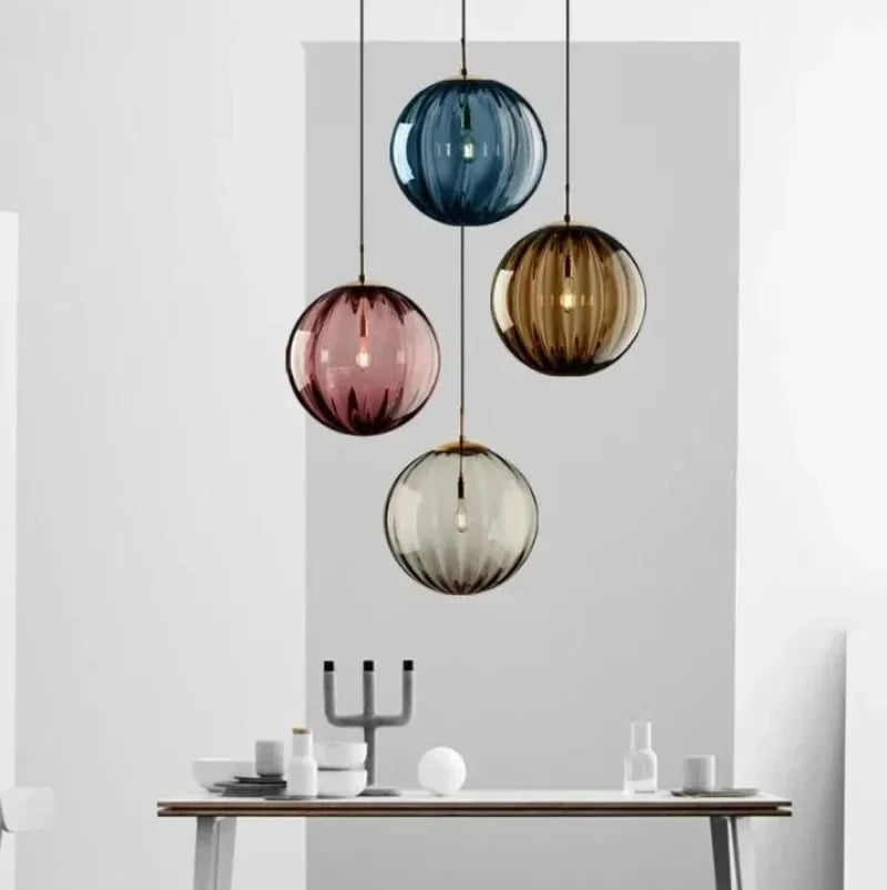 Colorful glass pendant lights hanging above a dining table with a neutral background