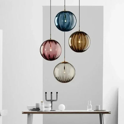 Colorful glass pendant lights hanging above a dining table with a neutral background