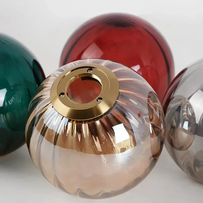 Close-up of a gold and clear glass sphere with other colored glass spheres on a white background