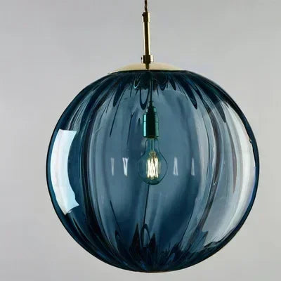 Blue glass pendant light with a visible bulb against a gray background