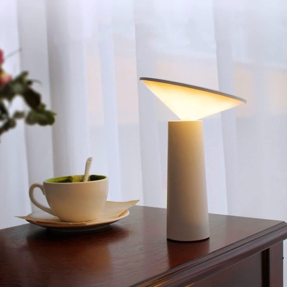 Small table lamp on a wooden surface with a cup and saucer in the background