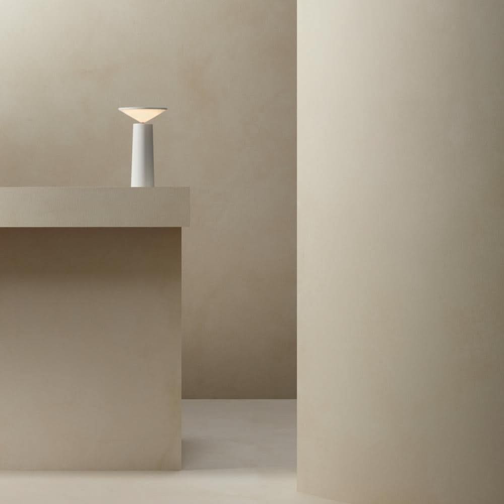 Minimalist scene with a lamp on a concrete surface against a plain wall.