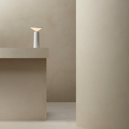 Minimalist scene with a lamp on a concrete surface against a plain wall.