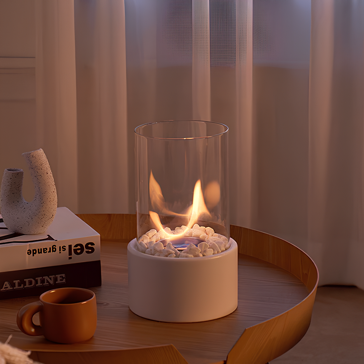 Small fire pit on a table with a cup and decorative items in a cozy setting
