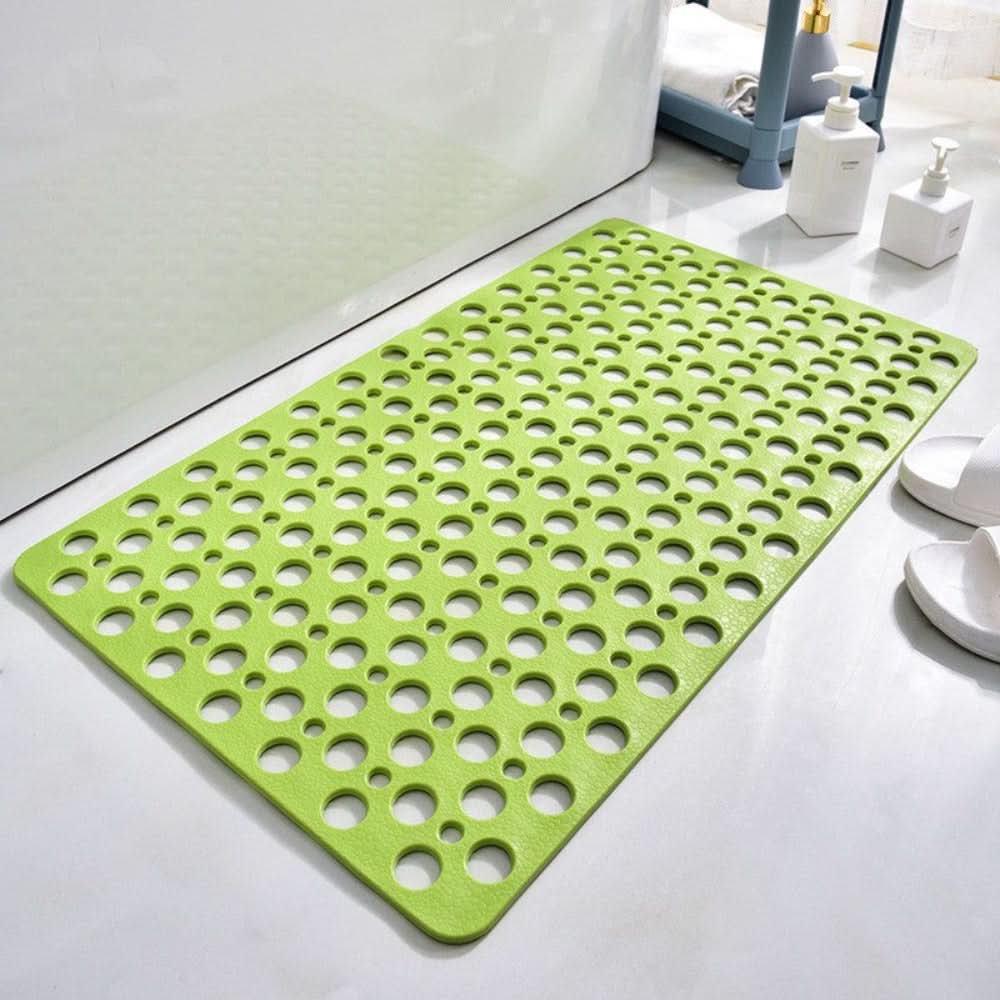 Green bath mat with circular holes on a bathroom floor
