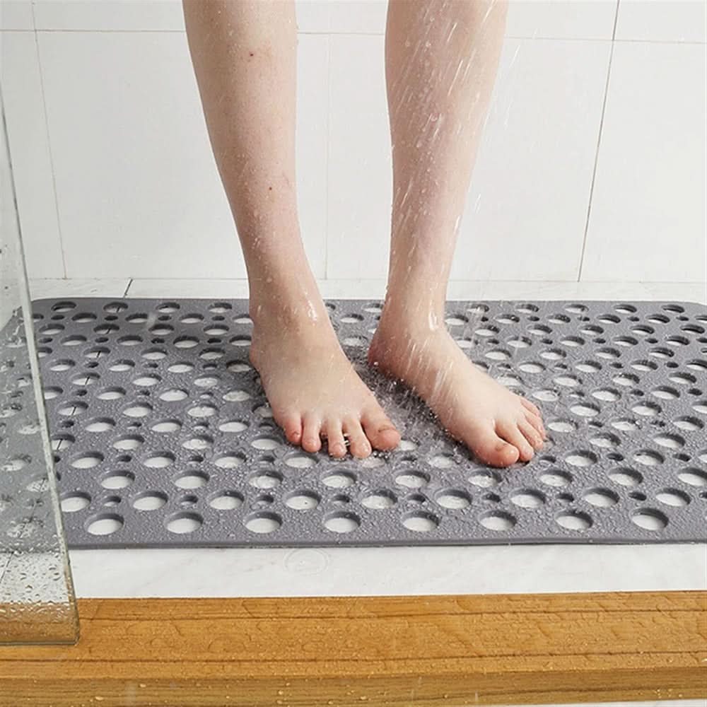 Person standing on a textured gray mat in a shower setting