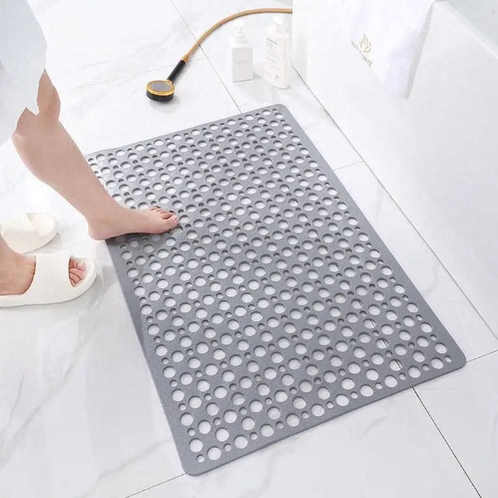 Gray textured bath mat on a white tiled bathroom floor with a person stepping onto it.
