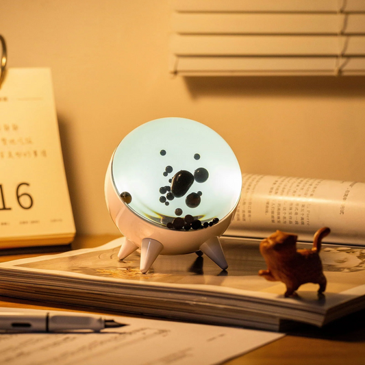 Decorative lamp with a circular design on top of a notebook with a small figurine beside it.