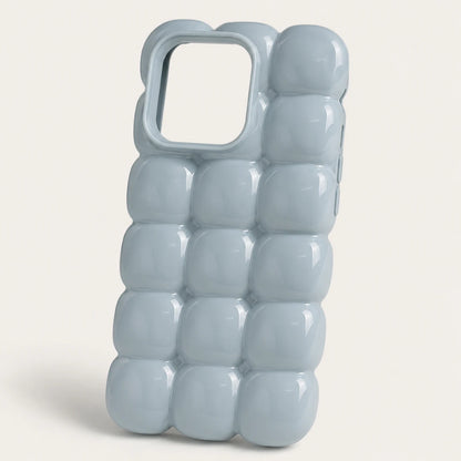 Josh & Tate - MarshBubble™ Puffy iPhone Case - A glossy, light blue phone case with a 3D bubble grid design and a large camera cutout, shown on a neutral off-white background.