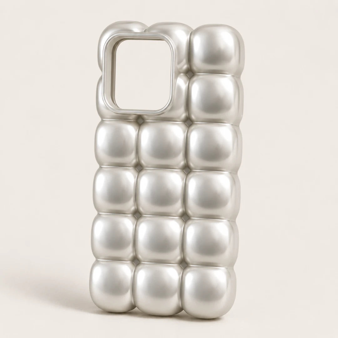 Josh & Tate - MarshBubble™ Puffy iPhone Case - A silver metallic phone case with a 3D bubbled, quilted texture and a square camera cutout, shown on a light beige background.
