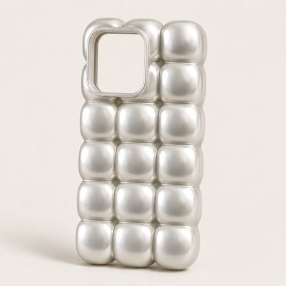 Josh & Tate - MarshBubble™ Puffy iPhone Case - A silver metallic phone case with a 3D bubbled, quilted texture and a square camera cutout, shown on a light beige background.