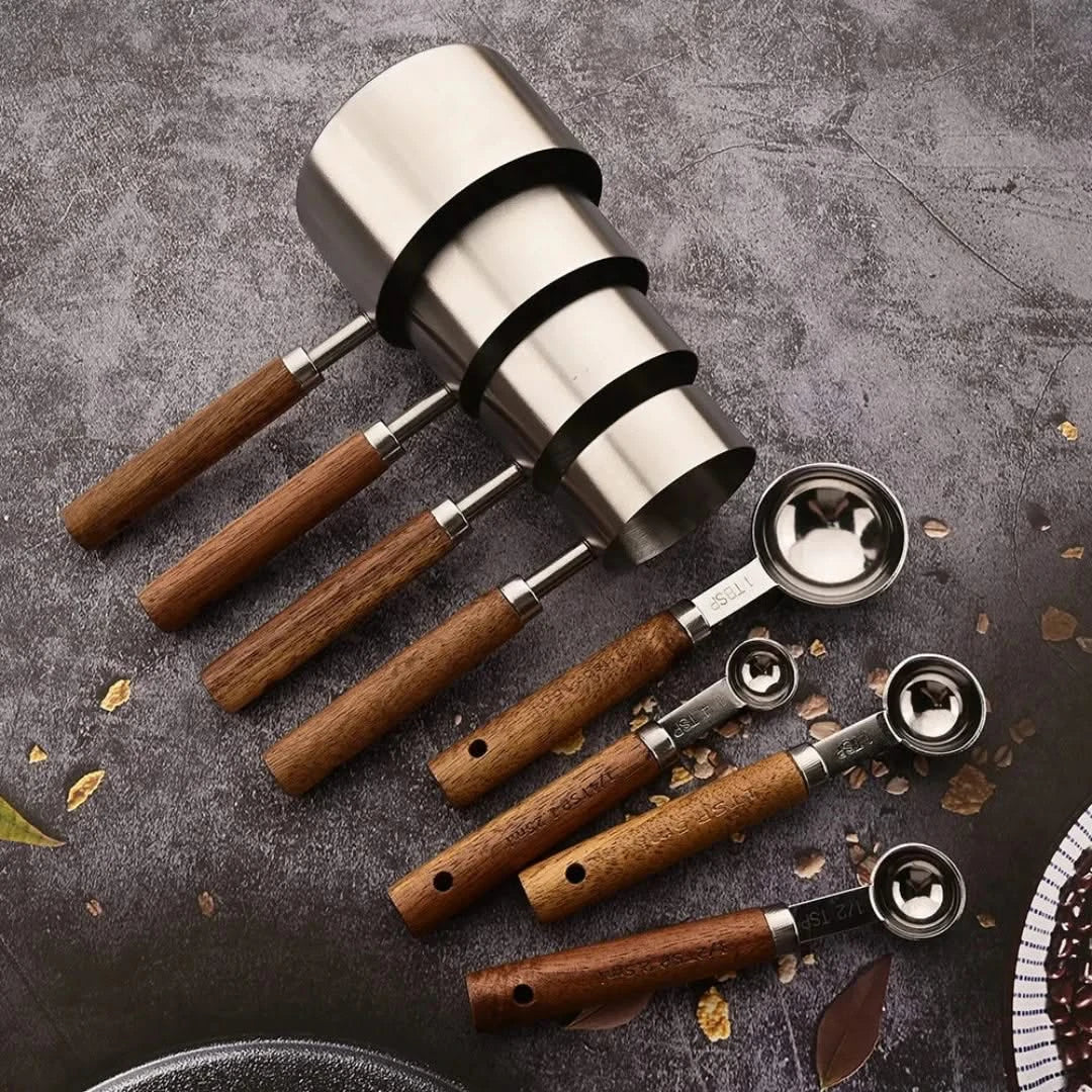 Josh & Tate - Measuring Spoon Set (Wood Handle) - Set of coffee tools including a silver tamper and multiple wooden-handled espresso scoops on a dark surface.