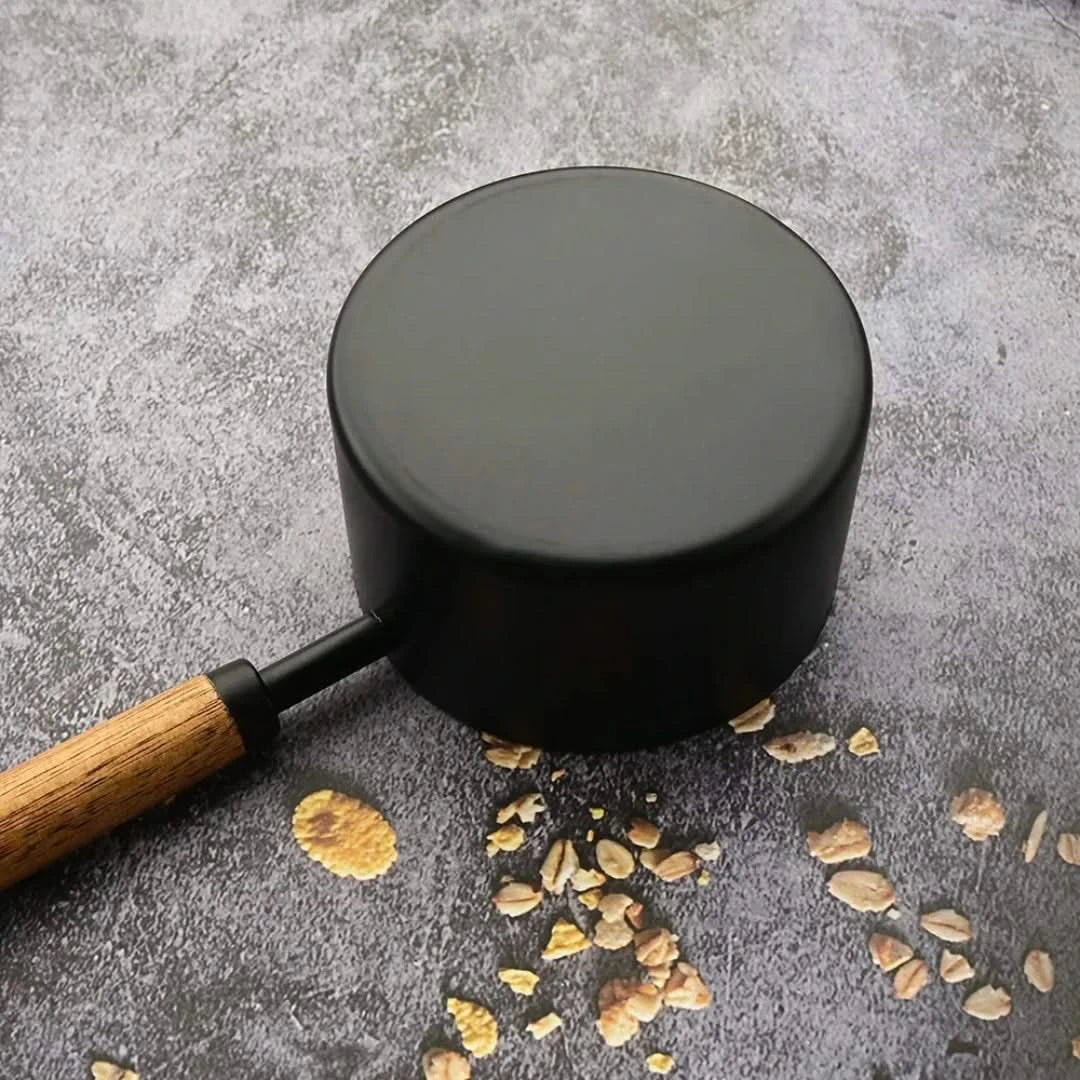Josh & Tate - Measuring Spoon Set (Wood Handle) - Black pot with wooden handle on a gray surface with small stones