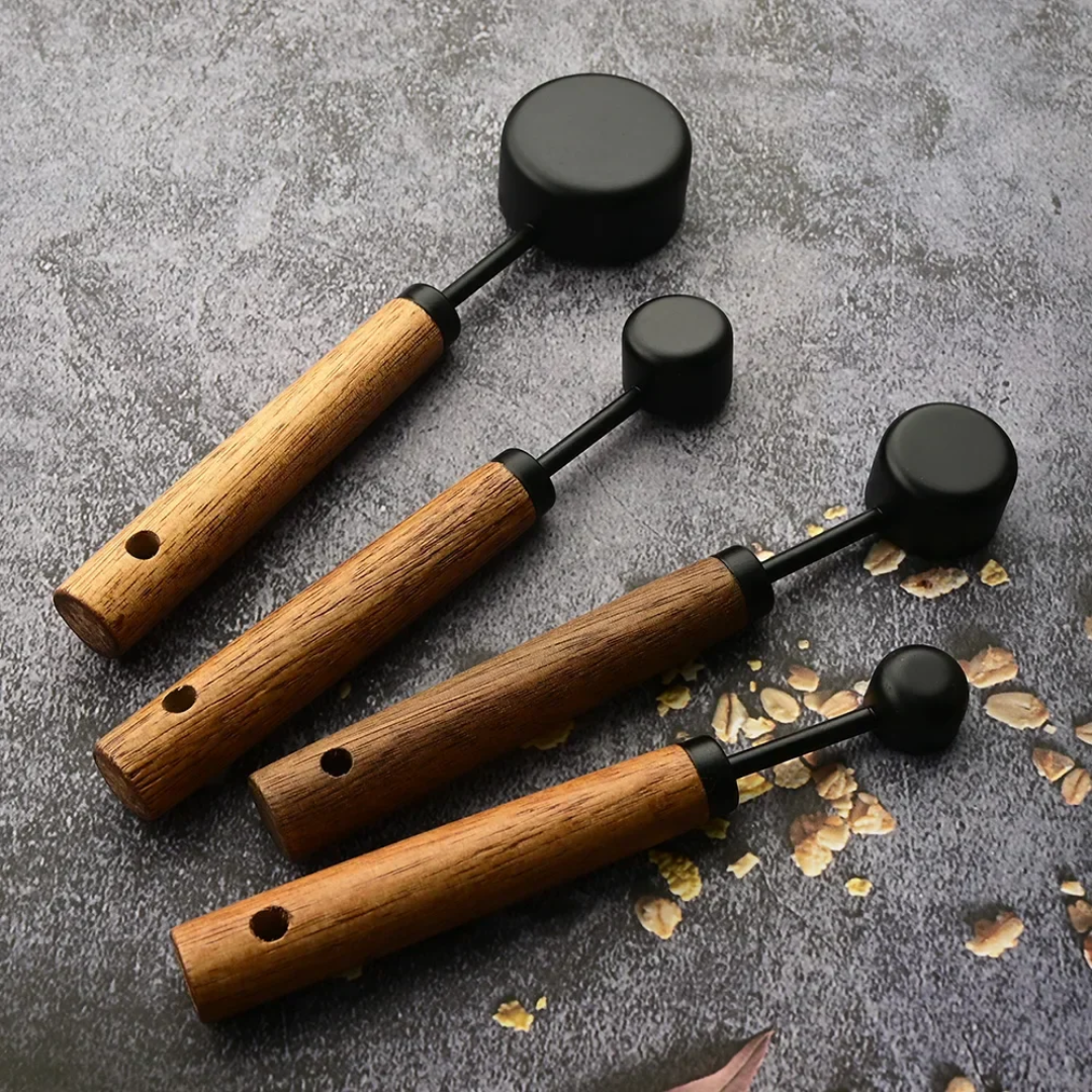 Set of four wooden-handled tools with black ends on a textured surface.