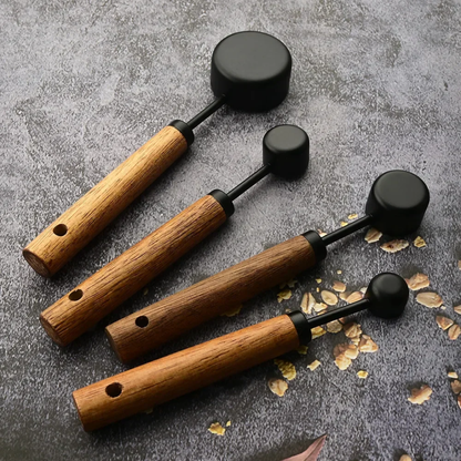 Set of four wooden-handled tools with black ends on a textured surface.