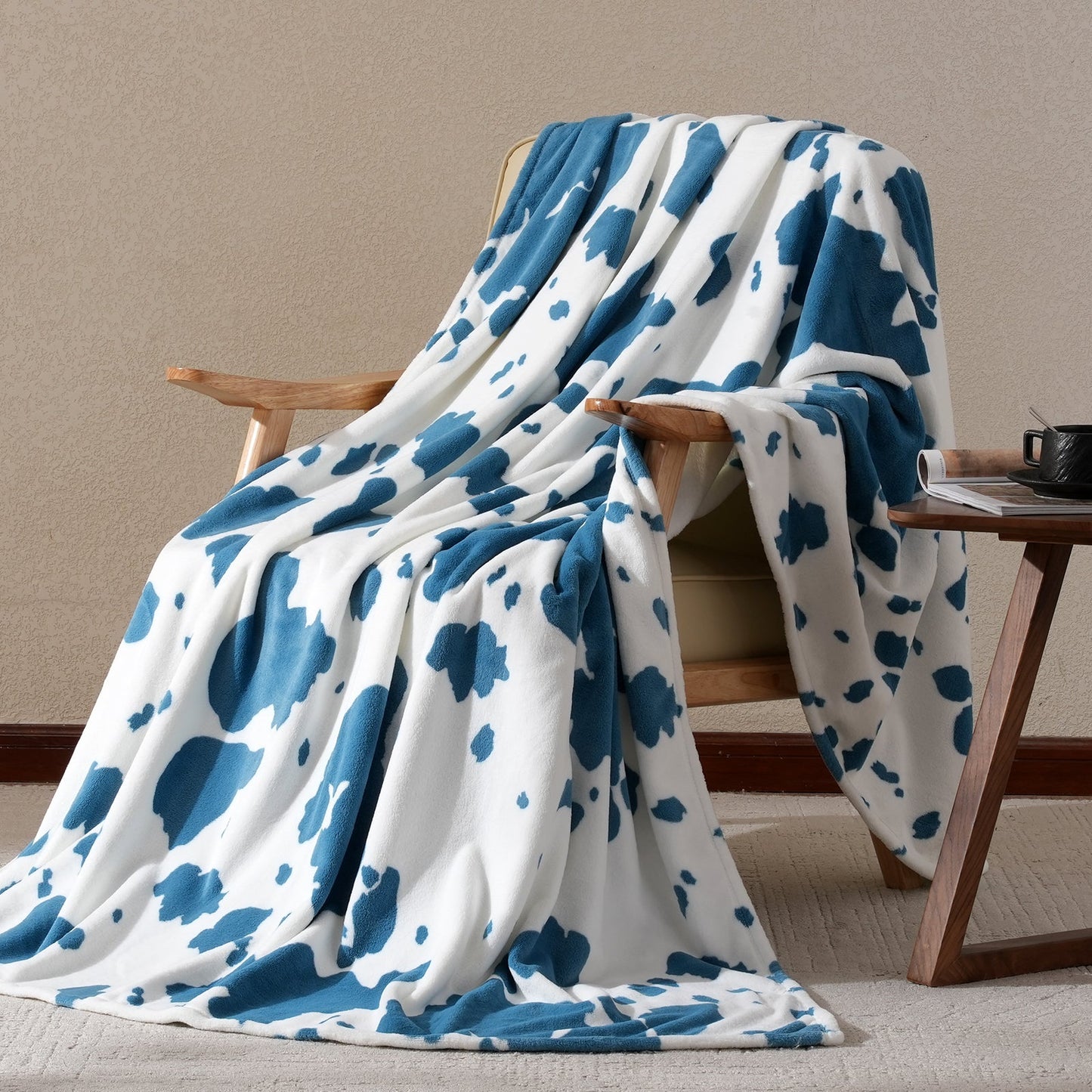 Blue and white patterned blanket draped over a wooden chair against a beige wall.