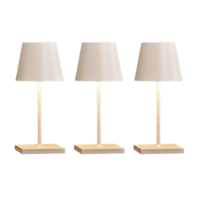 Three table lamps with beige lampshades and wooden bases on a white background