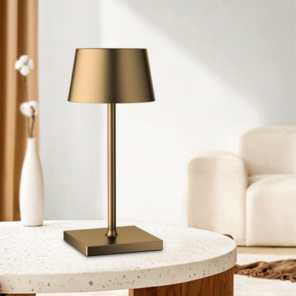 Gold table lamp on a round marble table with a vase and decorative items in a living room setting.
