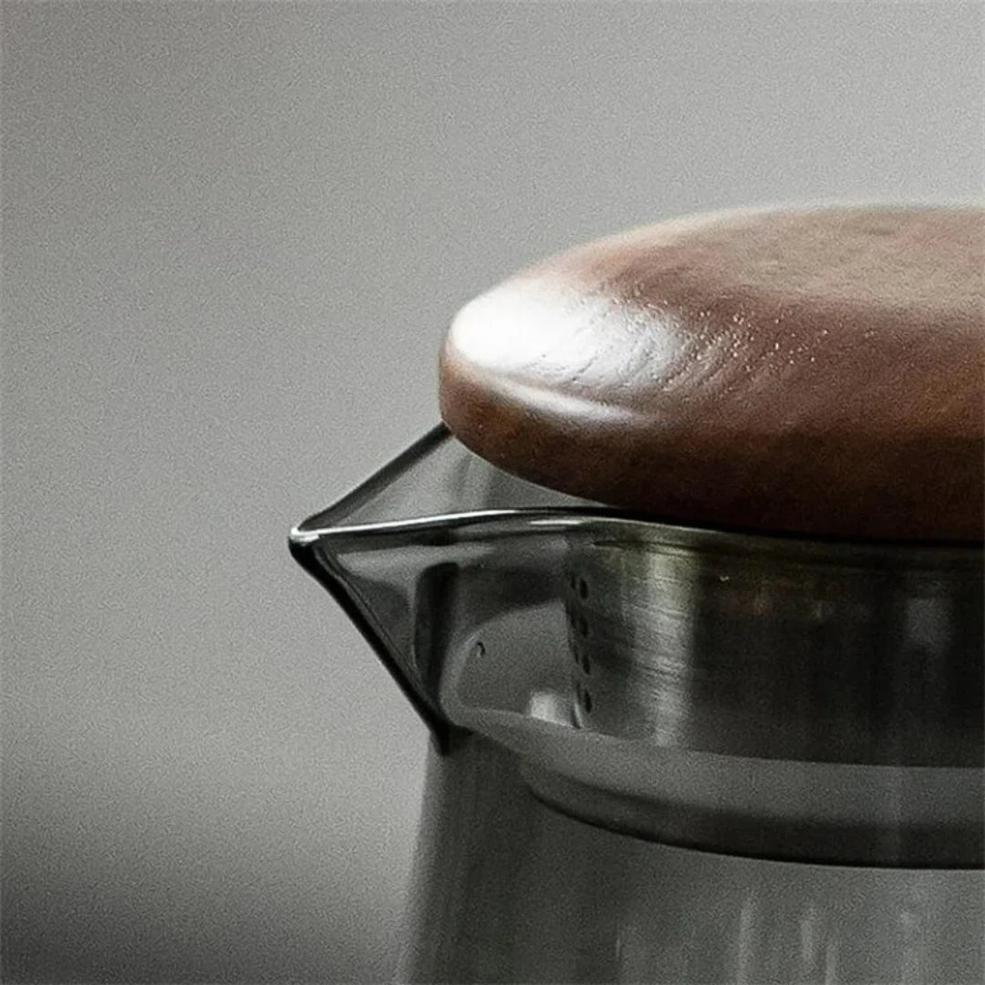 Josh & Tate - Montara Elegant Glass Pitcher - Close-up of a metal coffee filter with a brown coffee bean on a gray background